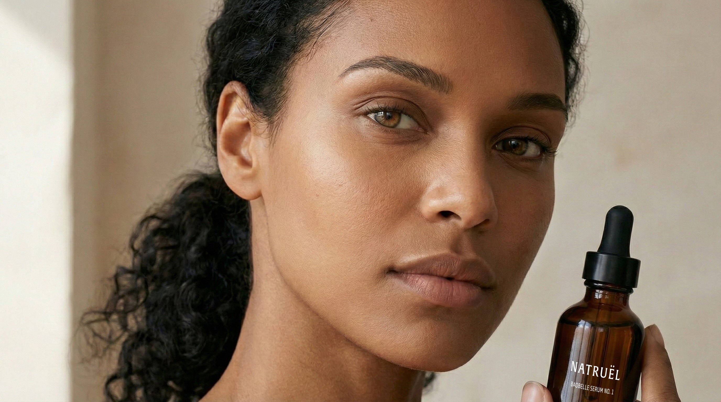 Model holding Natruël Baobelle Serum No. 1 botanical facial oil in natural light